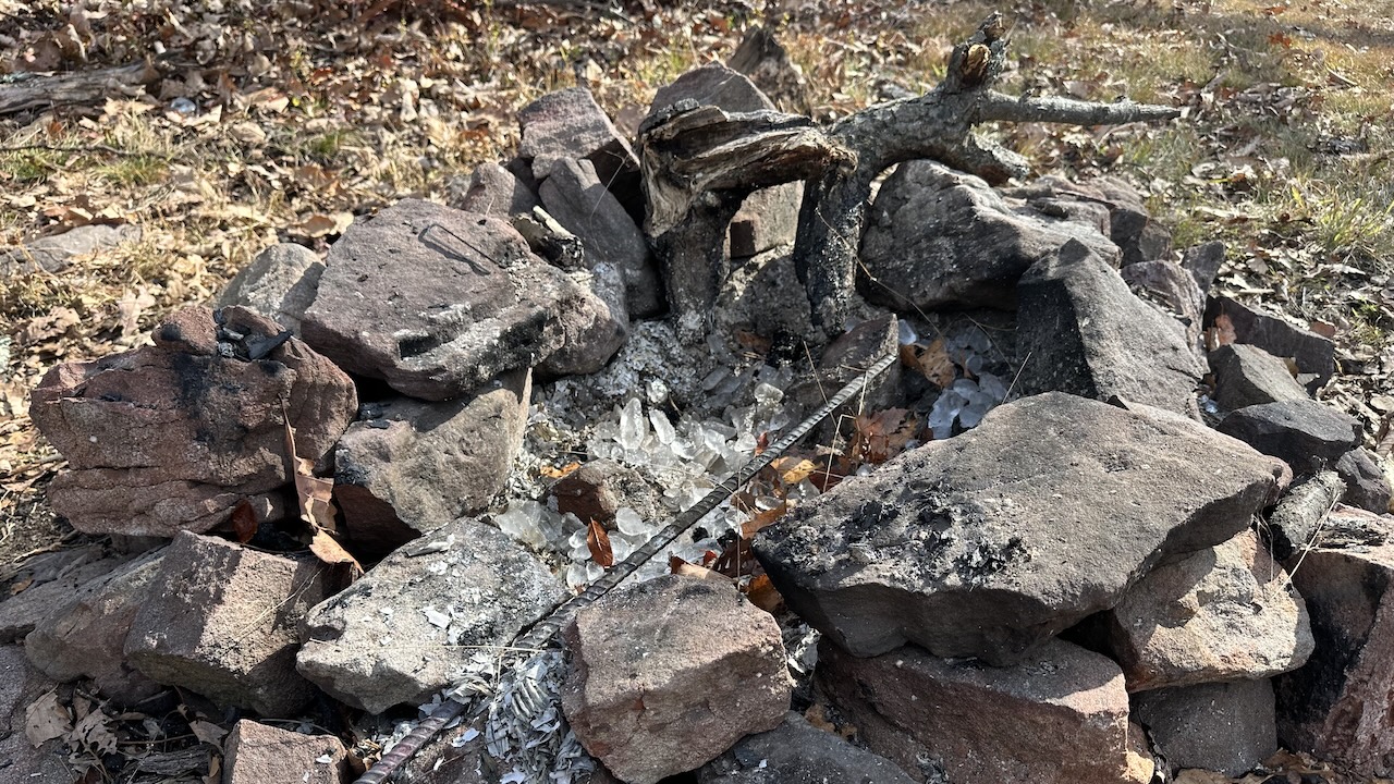 fire pit in woods with ice on top of ashes