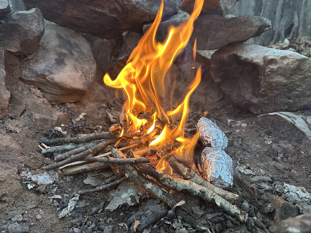 two potatoes at a campfire