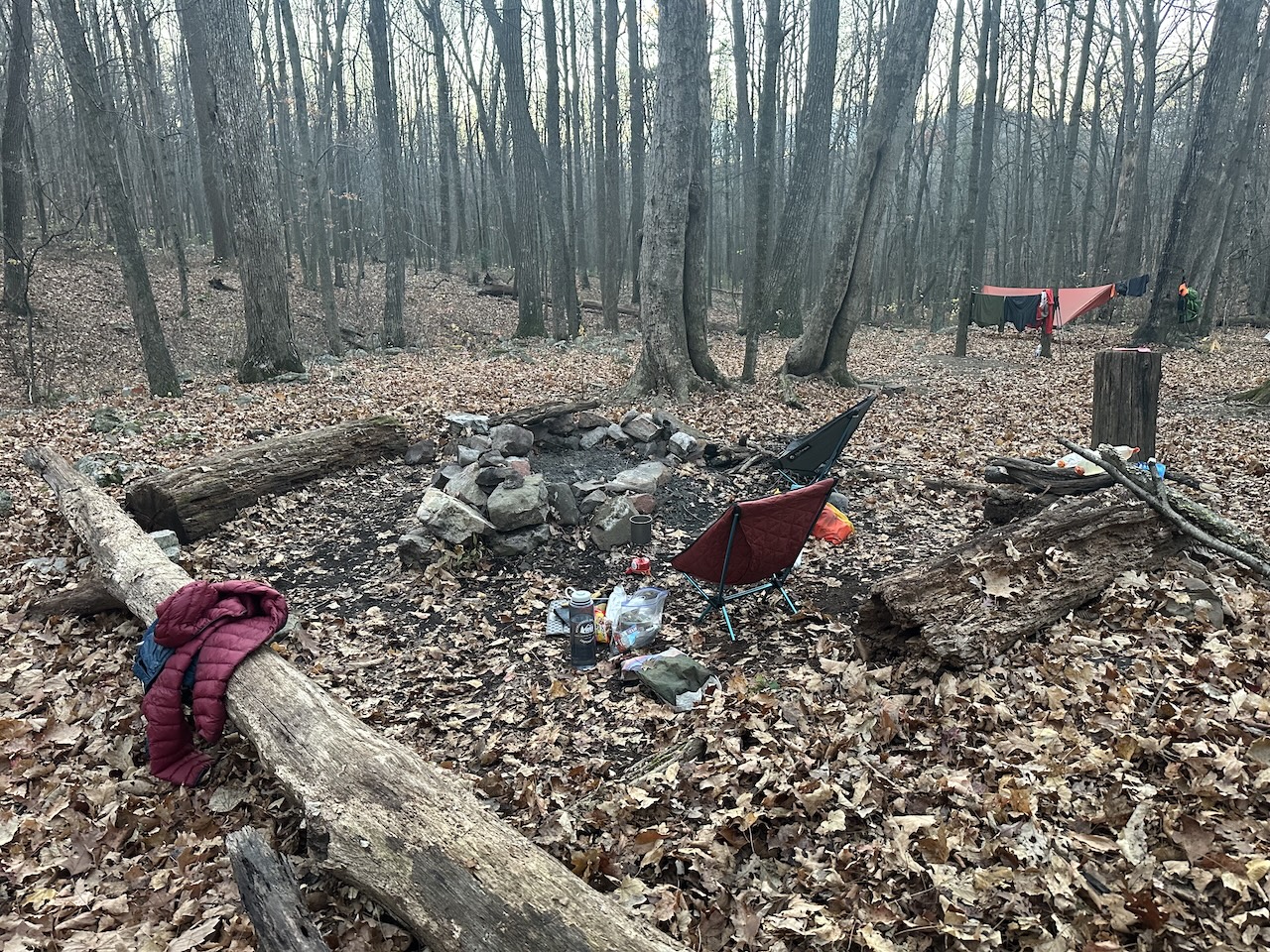 campsite with tent, hammock, camp chairs, and a fire ring